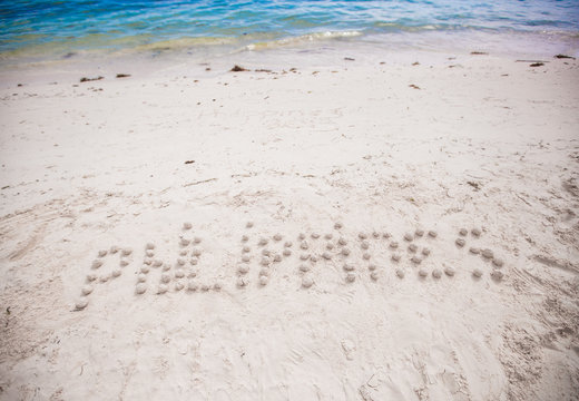 Philippines written in a sandy tropical beach