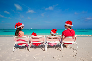 Happy family of four in Christmas Hats on white beach