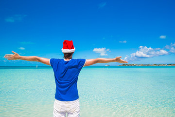 Young man in santa hat on tropical beach