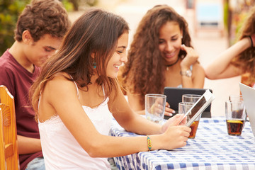 Teenage Friends Sitting At Caf‚ Using Digital Devices