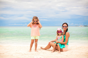Beautiful mother and her little daughters at exotic beach