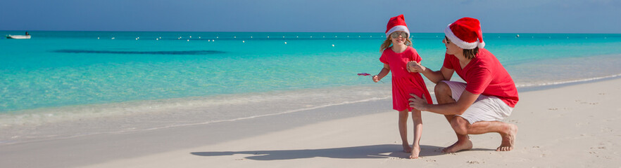 Little girl and happy dad in Santa Hat at exotic beach