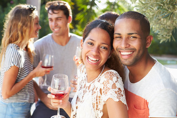 Couple With Friends Drinking Wine And Relaxing Outdoors