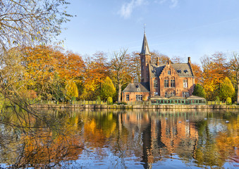 Fototapeta premium Budynek w stylu flamandzkim odzwierciedlający jezioro Minnewater, Brugia, Belgia