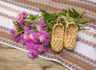 Bouquet of purple cornflowers and bast shoes