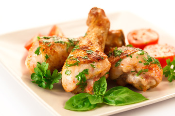Grilled chicken legs and vegetables on white background