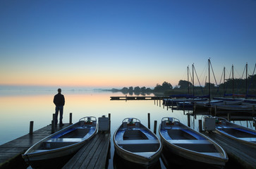 Man standing on a jetty during blue hour.