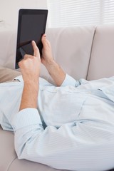 Casual man using tablet on the couch