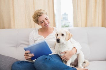 Happy blonde using tablet pc with puppy