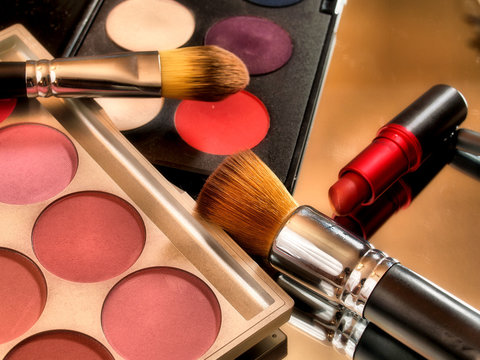 Make up color palette with red lipstick and brushes.