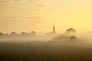 wieś i pole spowite w porannej mgle