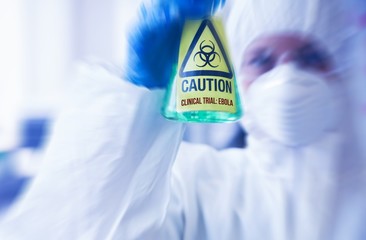 Scientist in protective suit holding beaker