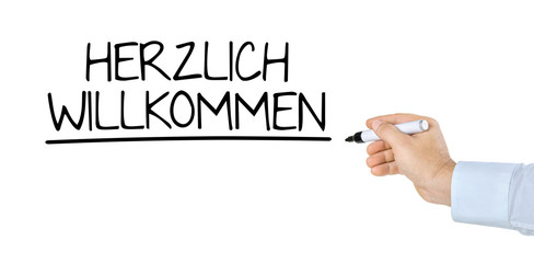 Hand mit Stift schreibt Herzlich Willkommen