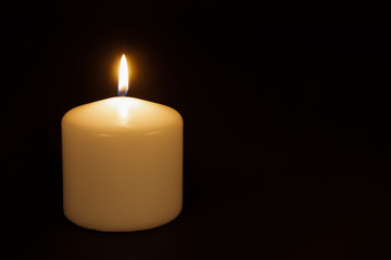 White candle burning against a black background