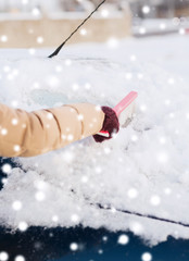 closeup of woman cleaning snow from car