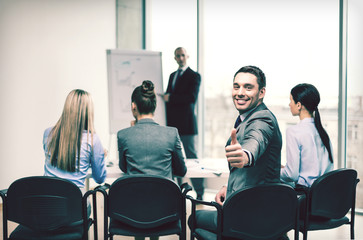 businessman with team showing thumbs up in office