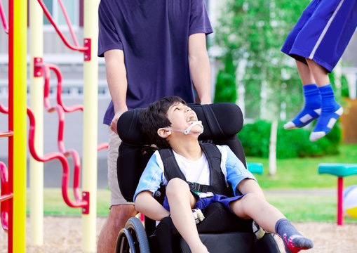 Disabled boy in wheelchair enjoying watching friends play at par