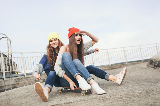 Two young  longboarding girl friends