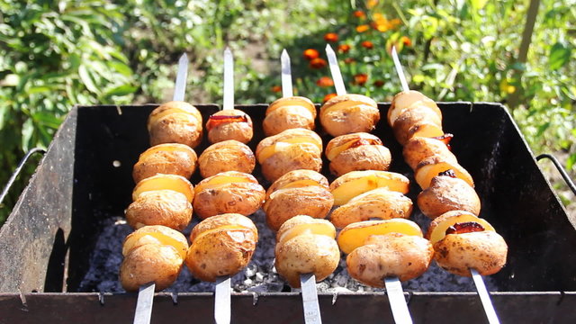 potato with pieces of bacon between them roast on coals