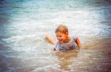 Fototapeta na wymiar boy at the sea lying in sand and waves