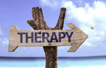 Therapy wooden sign on a beach background