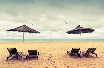 Sunbeds and umbrellas on empty sandy beach. Instagram toned phot