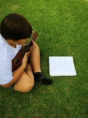 boy playing the ukulele on the grass in Hawaii