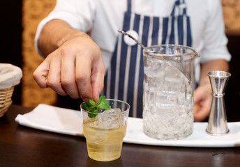Bartender is adding mint to the cocktail
