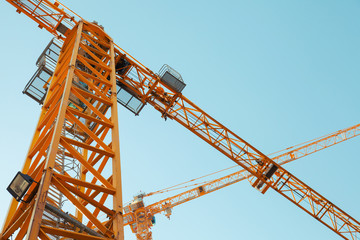 Fototapeta na wymiar Modern yellow construction cranes above blue sky