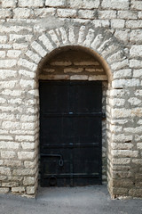 Fototapeta na wymiar Old stone wall and black metal door, background texture