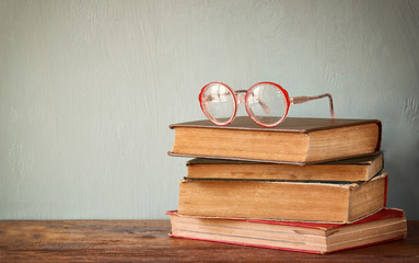 Old books with vintage glasses on a wooden table. retro filtered