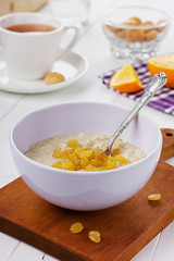Porridge with raisin in a bowl on the white table