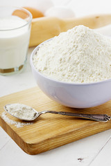 Flour in ceramic bowl with eggs and rolling pin