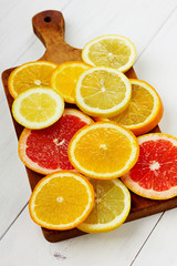 Citrus fruits slices on a brown wooden board on a white surface