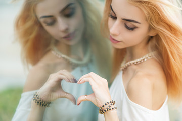 Young woman making a heart shape by hands.