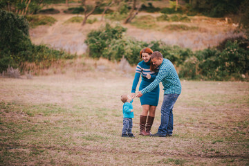 Naklejka na ściany i meble Happy family in blue stylish clothes walking in autumn forest