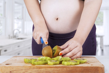 Healthy pregnant woman cuts fruit