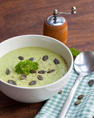 Homemade green broccoli cream soup served in white bowl