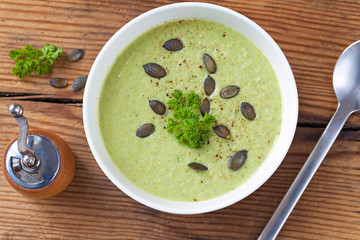 Homemade green broccoli cream soup served in white bowl