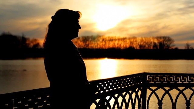 silhouette of pretty lady near clear lake, sunset, close-up
