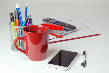 Mobile phone and office items on white tabletop