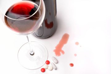 A glass of red wine with bottle and drugs on a white background