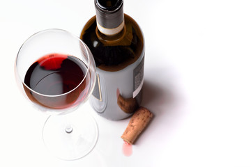 A glass of red wine with bottle and cork