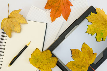 tablet with blank office notepads covered by autumn maple leaves