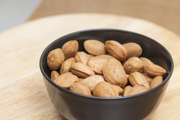 Almonds on a black bowl on wooden background