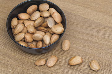 Almonds on a black bowl on wooden background