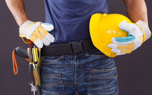 Close up of a worker with toolbelt and helmet against black back