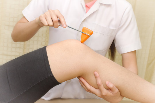 Female Doctor Doing Reflex Test On Patient's Knee