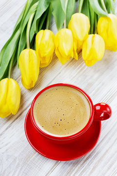 Cup of coffee and spring yellow tulips