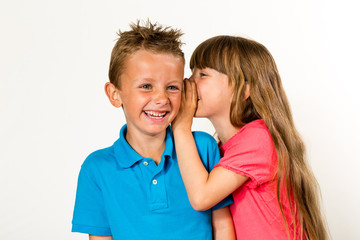 Young girl whispering to young boy